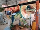 As crianças montam no dinossauro do parque temático para o equipamento do entretenimento
